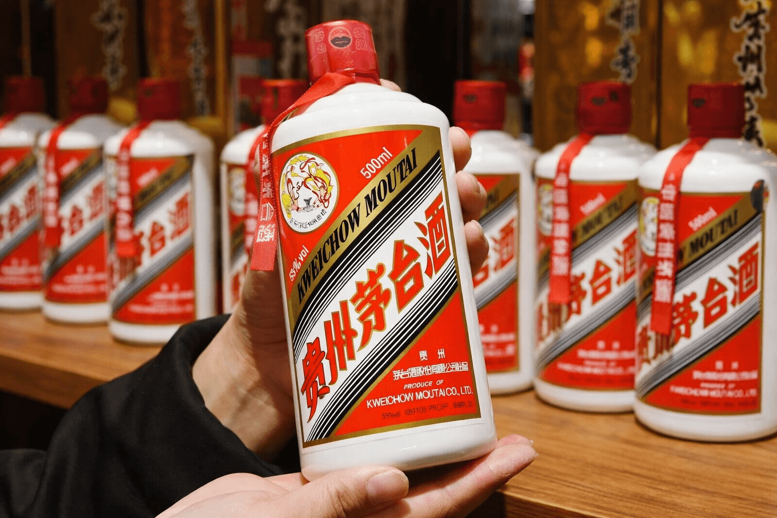 Hand holding a Kweichow Moutai bottle in front of a stocked retail shelf.