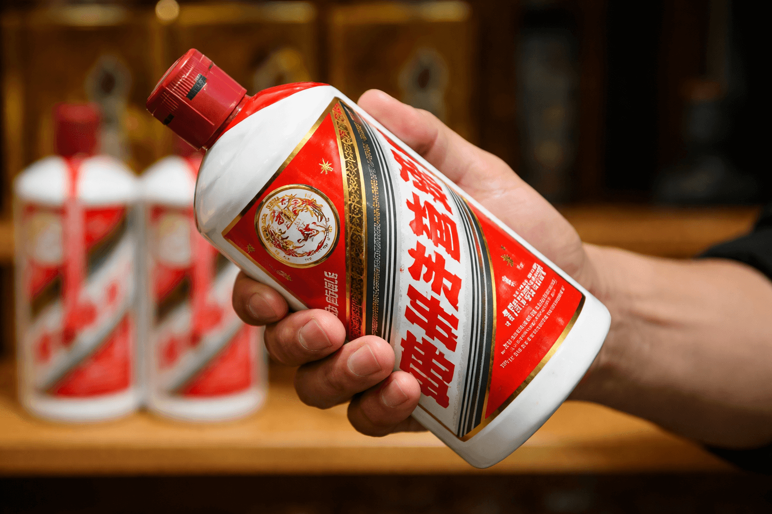 Hand holding a Kweichow Moutai bottle in front of a retail shelf display.